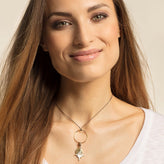 Woman wearing a necklace with a circular pendant and star charm on a neutral background