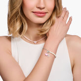 Woman wearing a necklace and bracelet with heart charms on a white background