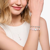 Woman wearing a bracelet with charms on a plain background