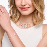 Woman wearing a silver necklace with colorful charms on a white background