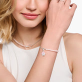 Woman wearing a bracelet with a pink charm on a white background