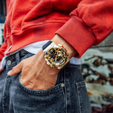 Person wearing a gold casio wristwatch with a red jacket and denim jeans.
