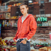 Person wearing a red hoodie in front of a fast food restaurant with an ATM sign wearing a Casio watch. 