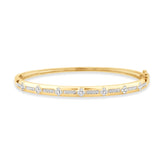 Yellow gold bangle bangle featuring alternating floral shaped diamond clusters and rows of small round diamonds set in a sleek, polished band.