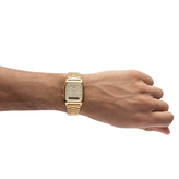 Gold tone Casio wristwatch on a person's wrist against a white background