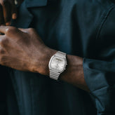Silver watch on a wrist with a dark shirt background