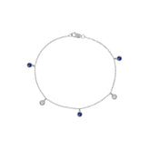 A delicate silver chain Bracelet with five small dangling charms, including two dark blue teardrop-shaped stones and three clear round-cut stones, displayed on a solid white background.