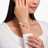Woman wearing a bracelet with lip and paris charms on a white background