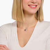 Woman wearing a silver necklace with a heart pendant on a white background