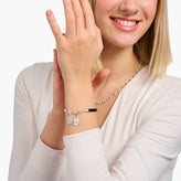 Woman wearing a silver bracelet with charms on a white background