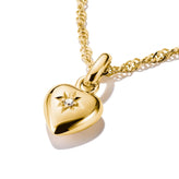 Gold heart-shaped pendant with a diamond on a gold chain against a white background