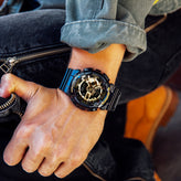 Person wearing a black and blue watch on a blurred background