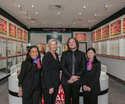 Zamel's Four staffs are standing in a Zamel's tore with promotional signs in the background.